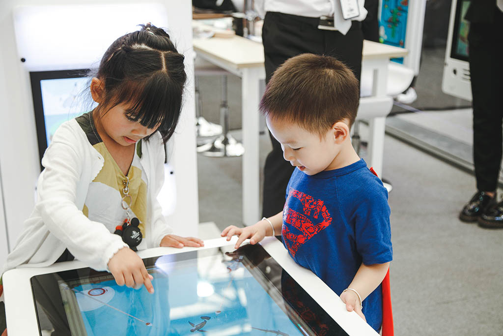Twee kindjes druk aan het spelen met de TouchTable van IKC